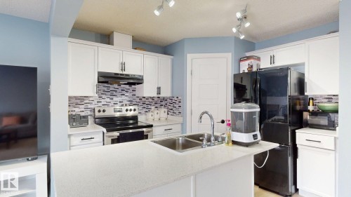 The kitchen features white cabinetry, a tiled backsplash, a double basin sink, and track lighting - 3613 11 Street, Edmonton, AB - Indoor Photo Showing Kitchen With Double Sink With Upgraded Kitchen