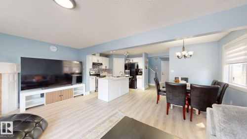 This open-concept living space features light-colored flooring, a kitchen with white cabinetry and an island, and a dining area with a chandelier - 3613 11 Street, Edmonton, AB - Indoor Photo Showing Other Room