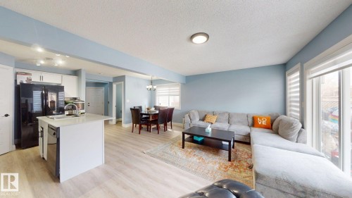 The property features an open-concept living area with light-toned flooring and light blue walls - 3613 11 Street, Edmonton, AB - Indoor Photo Showing Other Room