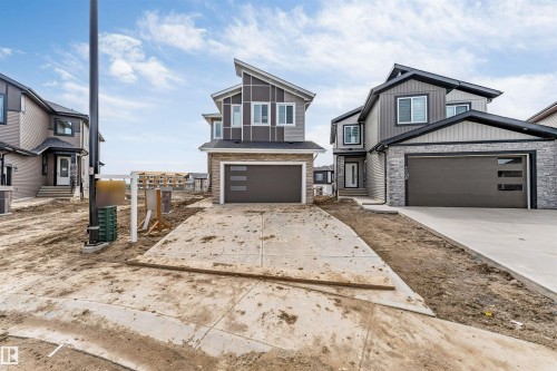 Contemporary two-story residence featuring a striking angular roofline and a dark brown garage door with horizontal frosted panels - 4006 35 St, Beaumont, AB - Outdoor With Facade