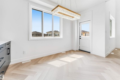 Bright interior with herringbone-patterned wood-finish flooring, white walls, and a contemporary linear crystal chandelier - 4006 35 St, Beaumont, AB - Indoor Photo Showing Other Room