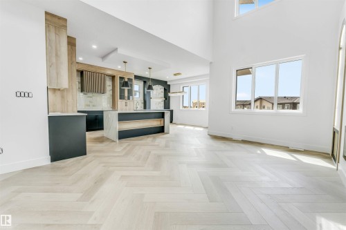 Open-concept living space featuring wood-finish herringbone flooring and high ceilings - 4006 35 St, Beaumont, AB - Indoor Photo Showing Other Room