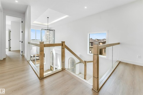 Upper-level hallway featuring wood-finish flooring, recessed lighting, and a contemporary glass and wood railing system - 4006 35 St, Beaumont, AB - Indoor Photo Showing Other Room