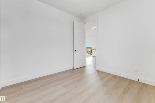 Light wood-finish flooring complements white walls and baseboards - 4006 35 St, Beaumont, AB - Indoor Photo Showing Other Room
