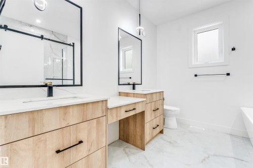 Double vanity featuring wood-finish cabinetry, white countertops, and integrated sinks with matte black fixtures - 4006 35 St, Beaumont, AB - Indoor Photo Showing Bathroom