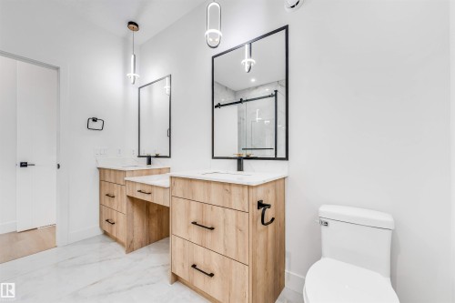 Bathroom featuring dual wood-finish vanities with undermount sinks and light countertops - 4006 35 St, Beaumont, AB - Indoor Photo Showing Bathroom
