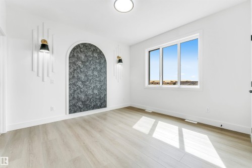 Contemporary interior design featuring a decorative arched accent wall with textured finish, flanked by two black and gold wall sconces - 4006 35 St, Beaumont, AB - Indoor Photo Showing Other Room
