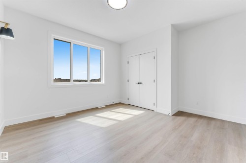 Bright interior space featuring a large three-panel window, light wood-finish flooring, white walls, and a contemporary flush-mount ceiling light - 4006 35 St, Beaumont, AB - Indoor Photo Showing Other Room