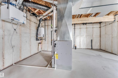 Unfinished basement featuring exposed wood joists, a concrete floor, installed insulation, an HVAC system, and a wall-mounted water heater - 4006 35 St, Beaumont, AB - Indoor Photo Showing Basement