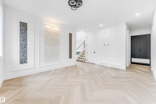 Open living space featuring herringbone-patterned wood-finish flooring - 4006 35 St, Beaumont, AB - Indoor Photo Showing Other Room