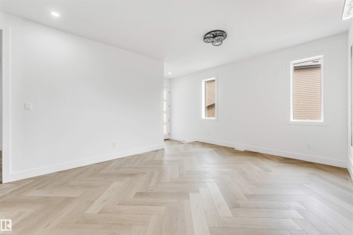 Herringbone wood-finish flooring complements the bright white walls - 4006 35 St, Beaumont, AB - Indoor Photo Showing Other Room