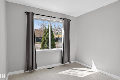 Windowed room featuring light gray wall paint, white trim, wood-finish flooring, and a street scene - 8722 112 Avenue, Edmonton, AB - Indoor Photo Showing Other Room