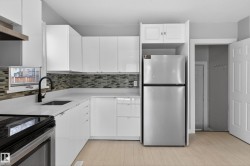 Kitchen featuring white cabinetry, light countertops, a mosaic tile backsplash, stainless steel appliances, and light wood-finish flooring - 