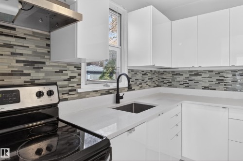 Modern kitchen featuring white cabinetry, a mosaic tile backsplash, and light-colored countertops - 8722 112 Avenue, Edmonton, AB - Indoor Photo Showing Kitchen