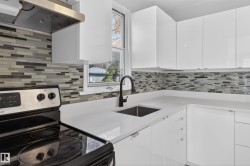 Modern kitchen featuring white cabinetry, a mosaic tile backsplash, and light-colored countertops - 