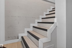 Staircase featuring wood-finish treads with dark anti-slip strips, white risers, and a textured concrete wall - 