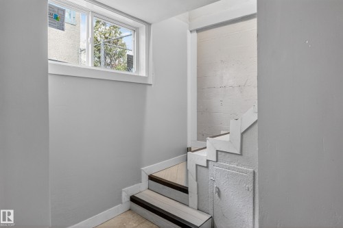 Staircase featuring wood-finish treads and white risers, framed by light gray walls - 8722 112 Avenue, Edmonton, AB - Indoor Photo Showing Other Room
