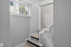 Staircase featuring wood-finish treads and white risers, framed by light gray walls - 