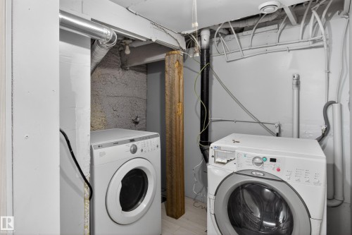 Dedicated laundry area featuring a front-loading washing machine and dryer, exposed utility piping, and a structural support beam - 8722 112 Avenue, Edmonton, AB - Indoor Photo Showing Laundry Room