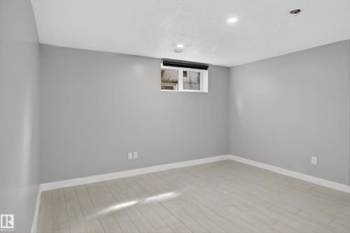 Spacious room featuring light wood-finish flooring, recessed lighting, and a window with a black roller shade - 8722 112 Avenue, Edmonton, AB - Indoor Photo Showing Other Room