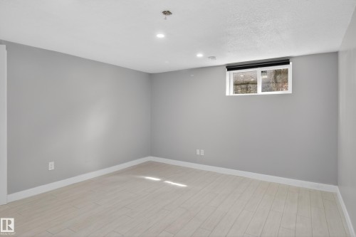 Spacious room featuring light wood-finish flooring, recessed lighting, and a white-framed window - 8722 112 Avenue, Edmonton, AB - Indoor Photo Showing Other Room