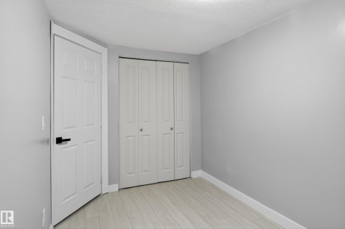 Interior room featuring light gray wall paint, white wood-finish flooring, and a white six-panel door with matte black hardware - 8722 112 Avenue, Edmonton, AB - Indoor Photo Showing Other Room