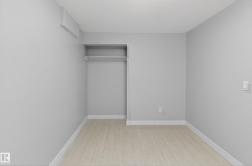 Light wood-finish flooring complements the neutral wall color - 8722 112 Avenue, Edmonton, AB - Indoor Photo Showing Other Room