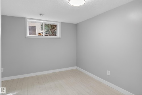 Bright interior space featuring light grey walls, white trim, and wood-finish flooring - 8722 112 Avenue, Edmonton, AB - Indoor Photo Showing Other Room