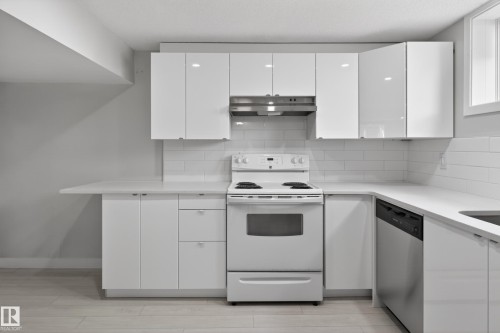 Contemporary kitchen featuring white flat-panel cabinetry, a white subway tile backsplash, and light-toned wood-finish flooring - 8722 112 Avenue, Edmonton, AB - Indoor Photo Showing Kitchen