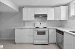 Contemporary kitchen featuring white flat-panel cabinetry, a white subway tile backsplash, and light-toned wood-finish flooring - 