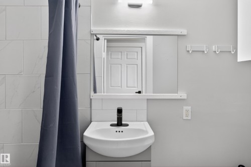 Wall-mounted pedestal sink with a matte black faucet - 8722 112 Avenue, Edmonton, AB - Indoor Photo Showing Bathroom