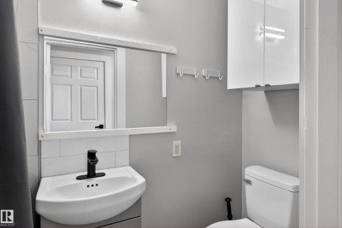 Modern bathroom featuring a corner-mounted sink with matte black faucet, subway tile backsplash, and wall-mounted storage cabinet - 8722 112 Avenue, Edmonton, AB - Indoor Photo Showing Bathroom