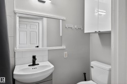 Modern bathroom featuring a corner-mounted sink with matte black faucet, subway tile backsplash, and wall-mounted storage cabinet - 