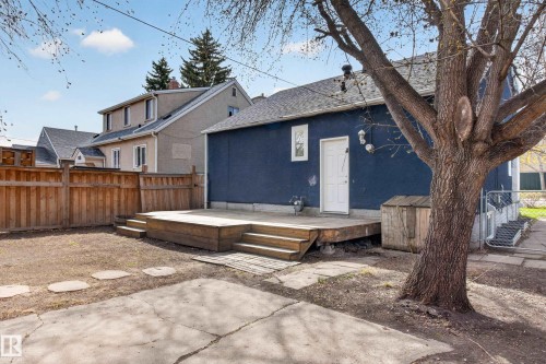 Rear exterior featuring a blue stucco finish, white entry door, and a multi-level wooden deck - 8722 112 Avenue, Edmonton, AB - Outdoor
