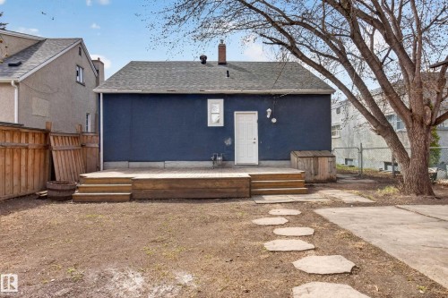 Rear exterior featuring a spacious wooden deck with steps, a white entry door, and a single window - 8722 112 Avenue, Edmonton, AB - Outdoor