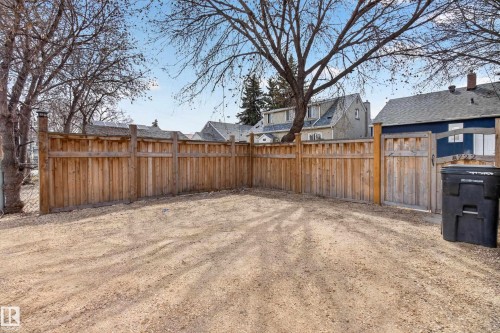 Expansive gravel yard featuring a wood privacy fence and a matching wood gate - 8722 112 Avenue, Edmonton, AB - Outdoor