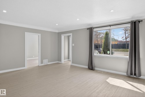 Spacious interior featuring light wood-finish flooring, neutral gray walls, and white trim - 8722 112 Avenue, Edmonton, AB - Indoor Photo Showing Other Room