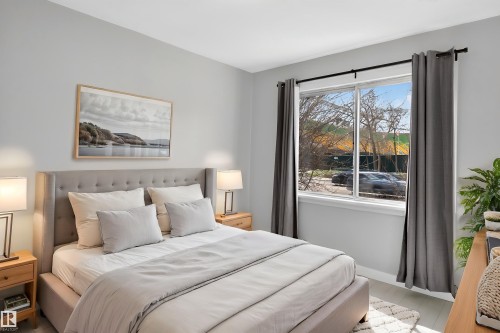 Bright bedroom featuring a large window, light-toned walls, and wood-finish flooring - 8722 112 Avenue, Edmonton, AB - Indoor Photo Showing Bedroom