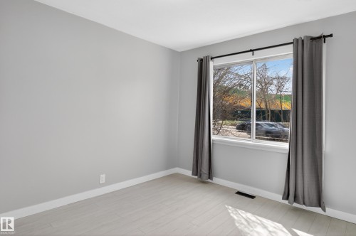 Bright room with a large window, neutral gray walls, and light wood-finish flooring - 8722 112 Avenue, Edmonton, AB - Indoor Photo Showing Other Room