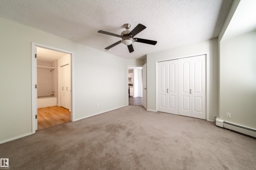 Carpeted interior space featuring a ceiling fan, light-colored walls, and a double-door closet with panel detailing - 302 9138 83 Avenue, Edmonton, AB - Indoor Photo Showing Other Room