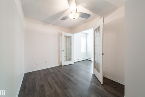 Room featuring wood-finish flooring, white walls, and a ceiling fan with integrated lighting - 302 9138 83 Avenue, Edmonton, AB - Indoor Photo Showing Other Room
