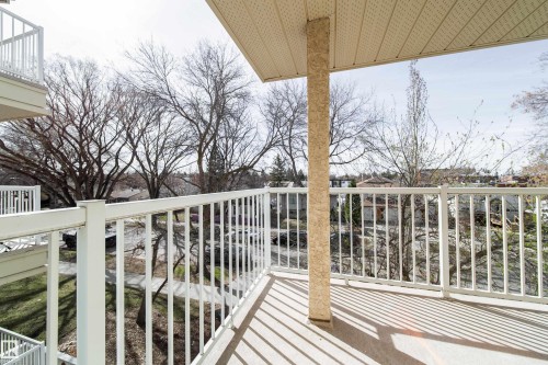 Spacious balcony featuring white metal railings, a textured support column, and an acoustic panel ceiling - 302 9138 83 Avenue, Edmonton, AB - Outdoor With Balcony With Exterior