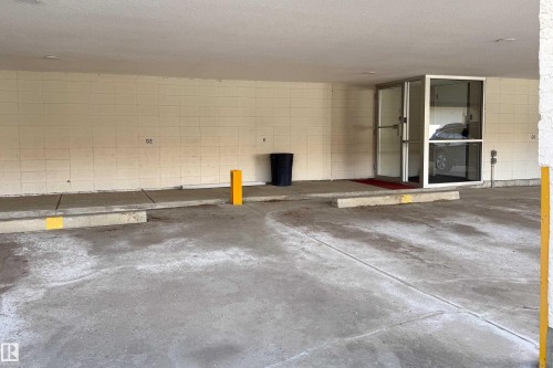 Covered parking area featuring concrete flooring and a block wall - 302 9138 83 Avenue, Edmonton, AB - Indoor Photo Showing Garage