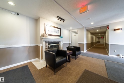 Lobby area featuring a decorative fireplace with a tile surround and white mantel - 302 9138 83 Avenue, Edmonton, AB - Indoor With Fireplace