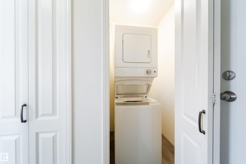 Dedicated laundry closet featuring a white stacked washer and dryer unit - 302 9138 83 Avenue, Edmonton, AB - Indoor Photo Showing Laundry Room