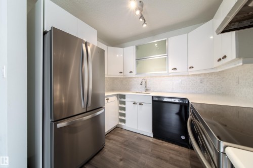 Modern kitchen featuring stainless steel appliances, white cabinetry, quartz-finish countertops, and wood-finish flooring - 302 9138 83 Avenue, Edmonton, AB - Indoor Photo Showing Kitchen