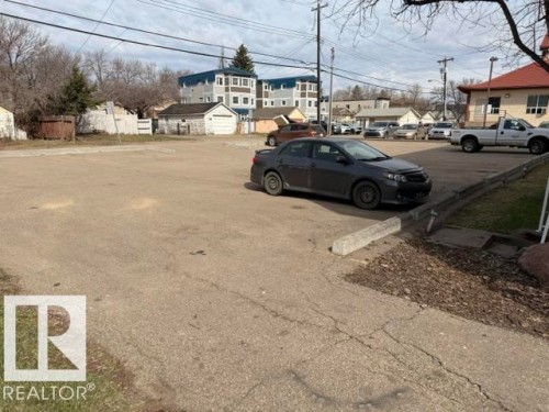 Paved parking area featuring concrete parking barriers and bordering grass - 201 11324 97 Street Nw, Edmonton, AB - Outdoor
