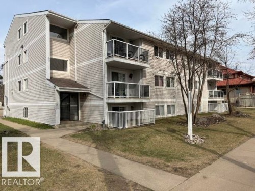 Multi-level residential building featuring light-colored siding, multiple windows, and individual balconies with glass and white metal railings - 201 11324 97 Street Nw, Edmonton, AB - Outdoor
