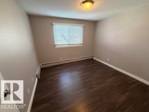 Room featuring dark wood-finish flooring, light neutral-toned walls, and white trim - 201 11324 97 Street Nw, Edmonton, AB - Indoor Photo Showing Other Room