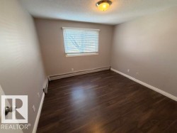 Room featuring dark wood-finish flooring, light neutral-toned walls, and white trim - 
